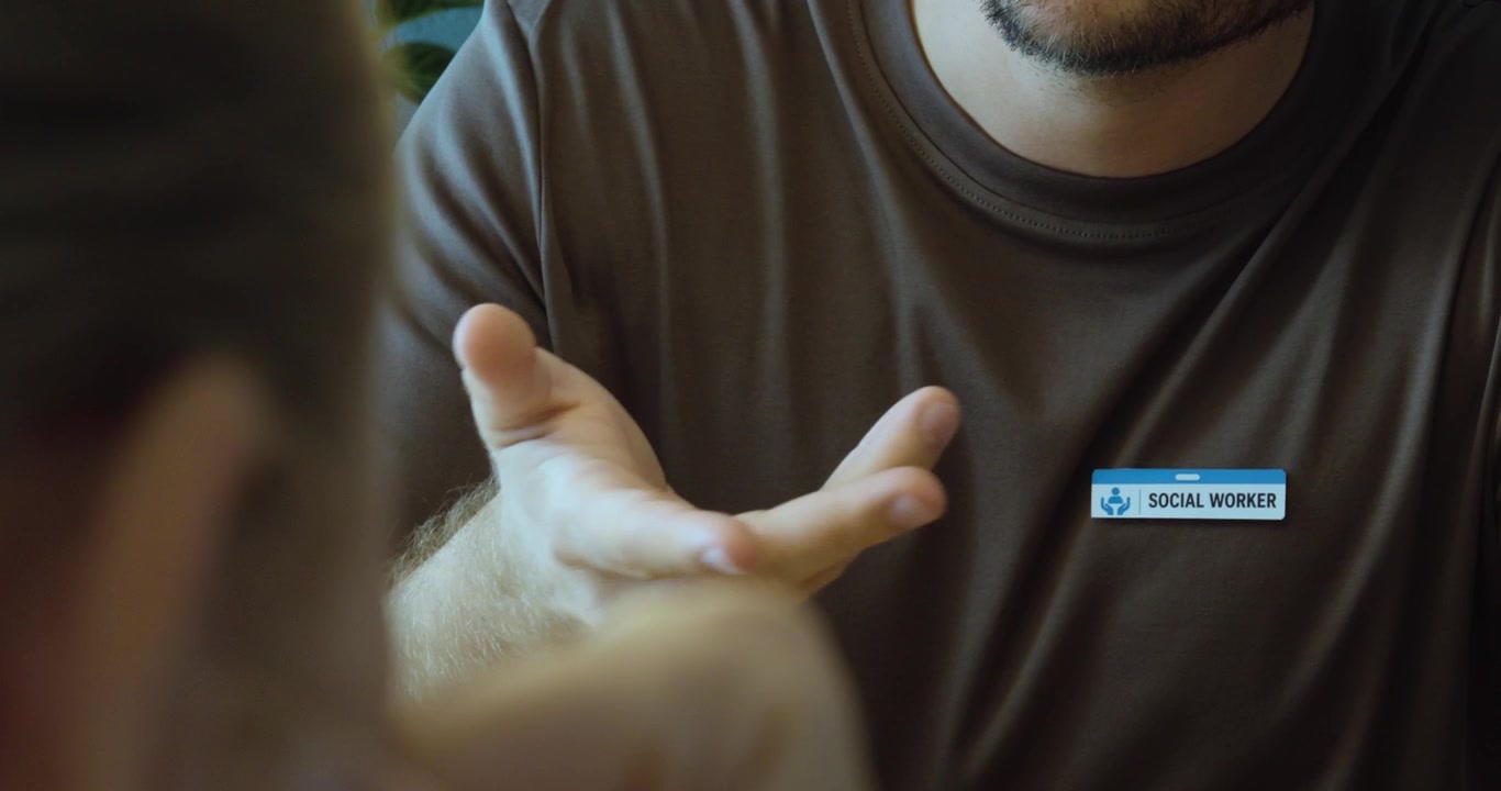 Close-up of a social worker speaking and gesturing during a face-to-face support and counseling session.