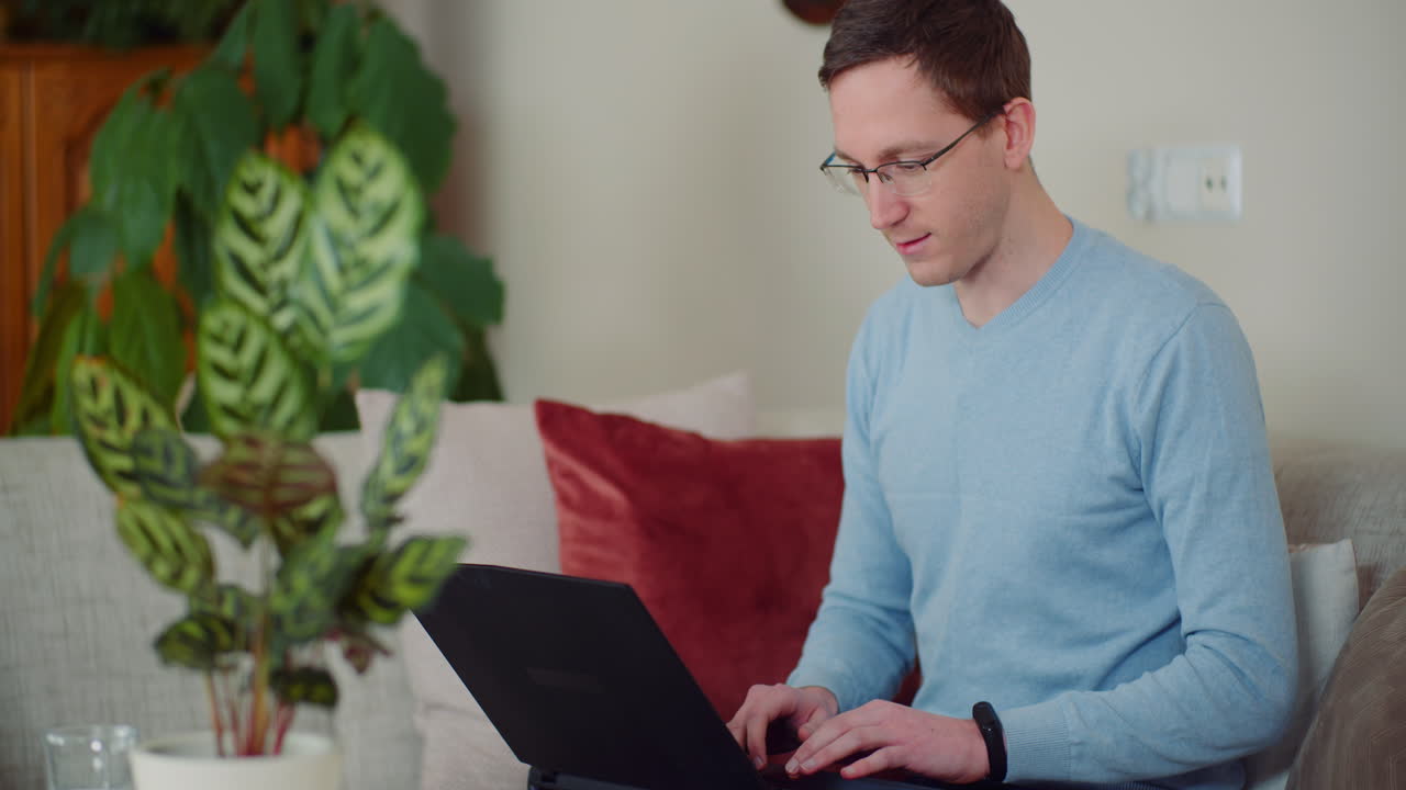 Busy Businessman Typing On Laptop While Siting On A Sofa In Living Room