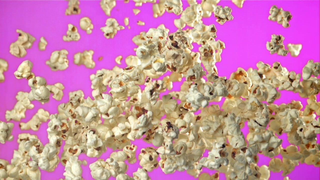 Popcorn che Volano e Cadono al Rallentatore su Sfondo Magenta