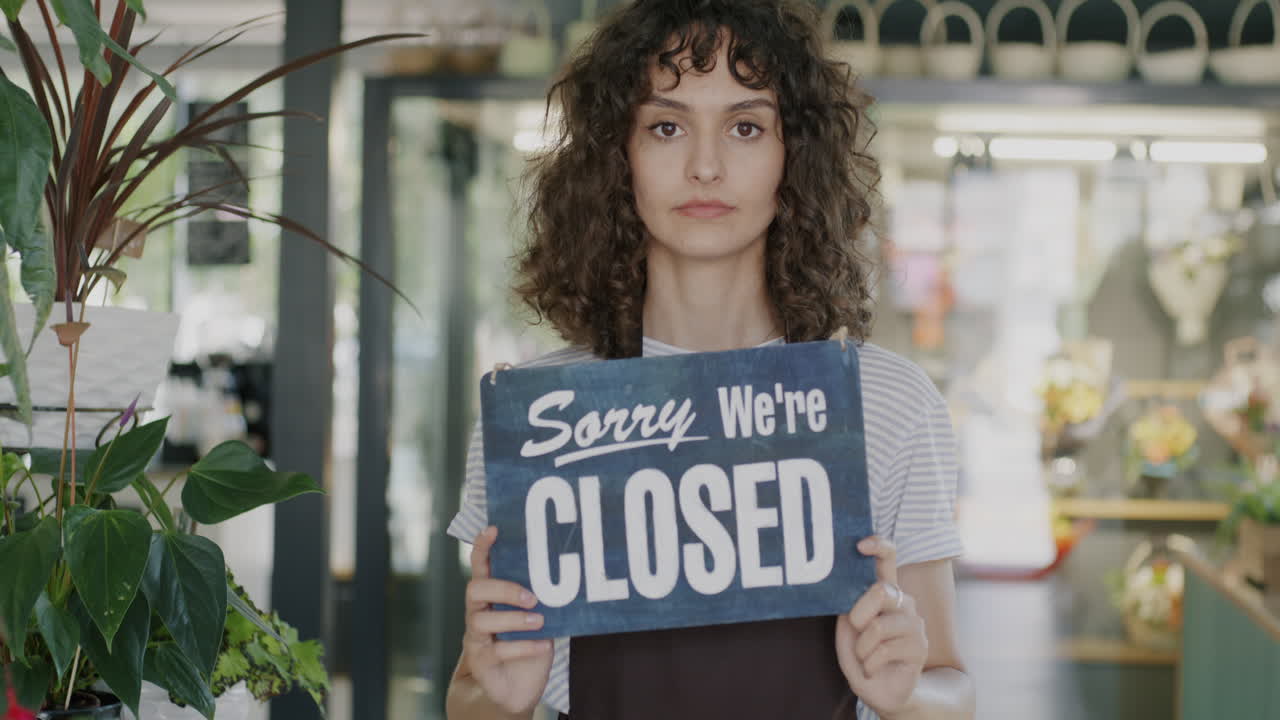 Woman Holding Closed Sign in a Floral Shop