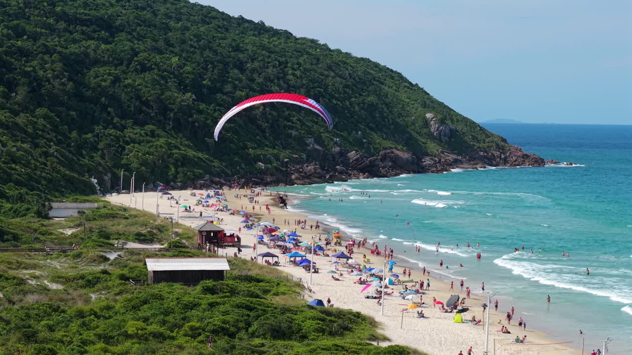 Brezilya, Santa Catarina, Florianopolis'teki Praia dos Ingleses yakınlarındaki sahil şeridinin üzerinde uçan motorlu yamaç paraşütü. Havadan takip çekimi.