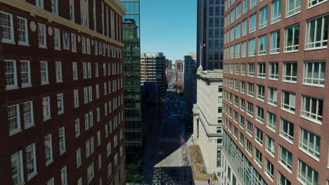 Backwards-fly-above-downtown-street.-Revealing-of-multistorey-buildings-with-brick-facades.-Boston,-USA
