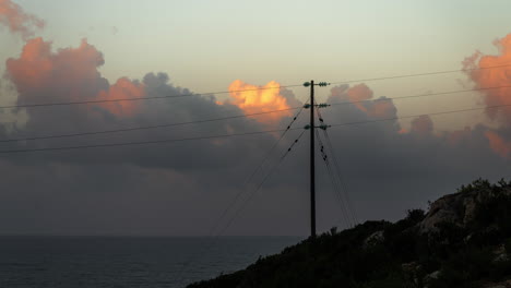 sunset over the sea with power lines