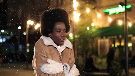 vista de cerca de una mujer afroamericana que tiene frío y trata de calentarse en la calle mientras nieva en navidad