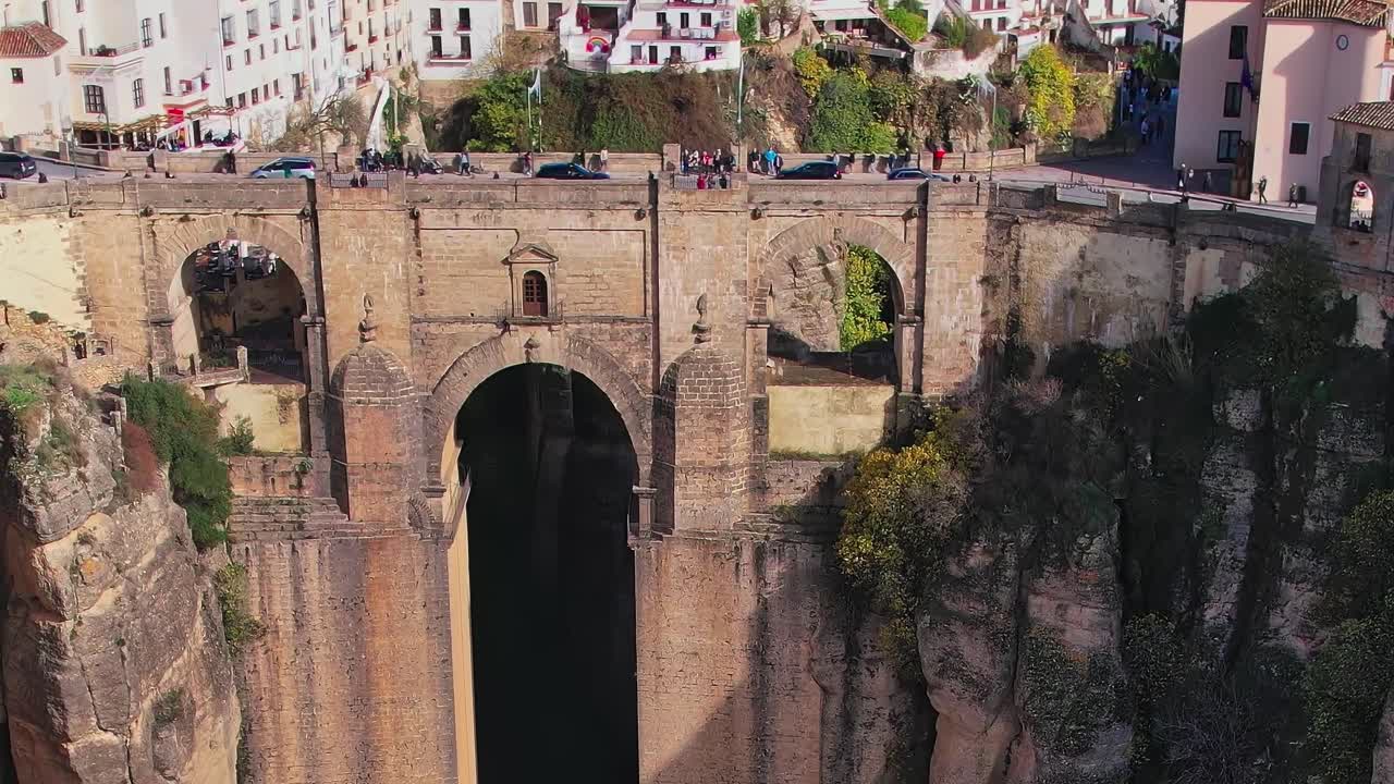 Vistas de un puente antiguo en Málaga durante un día ajetreado con turistas caminando.