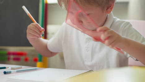 Diligent-boy-draws-circle-with-plastic-mould-and-pencil