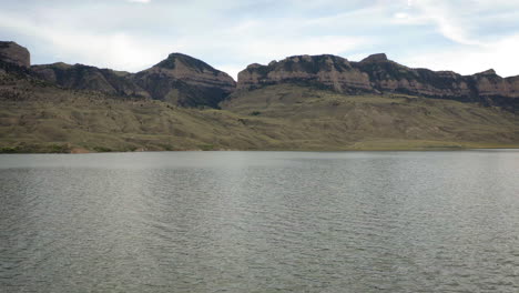 scenic view of a lake with rugged mountains under a cloudy sky
