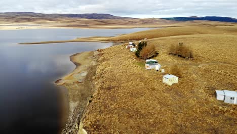 cabañas de pesca remotas sentadas junto al lago de agua oscura en el centro de otago, nueva zelanda.