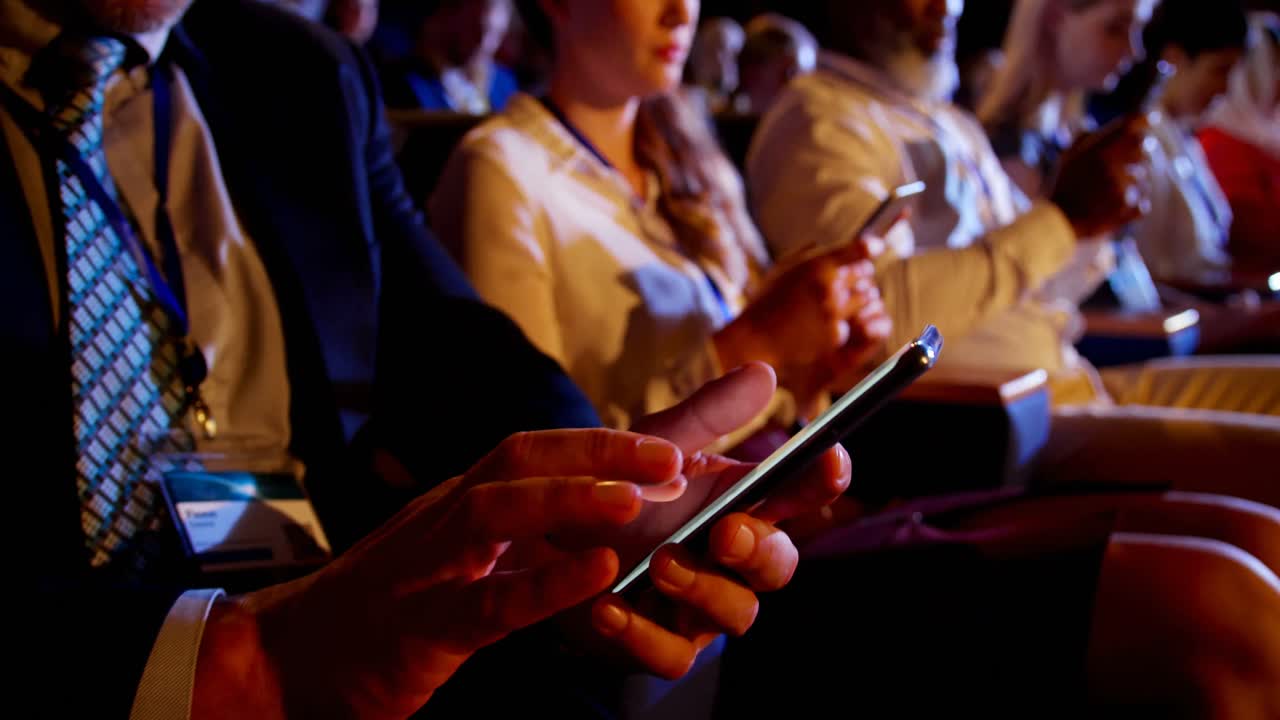 Multi-ethnic business people using mobile phone during business seminar in auditorium 4k