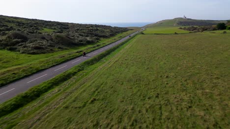 Toma-Aérea-Amplia-De-Un-Piloto-En-Una-Honda-Africa-Twin-En-Beachy-Head-En-Un-Día-Soleado