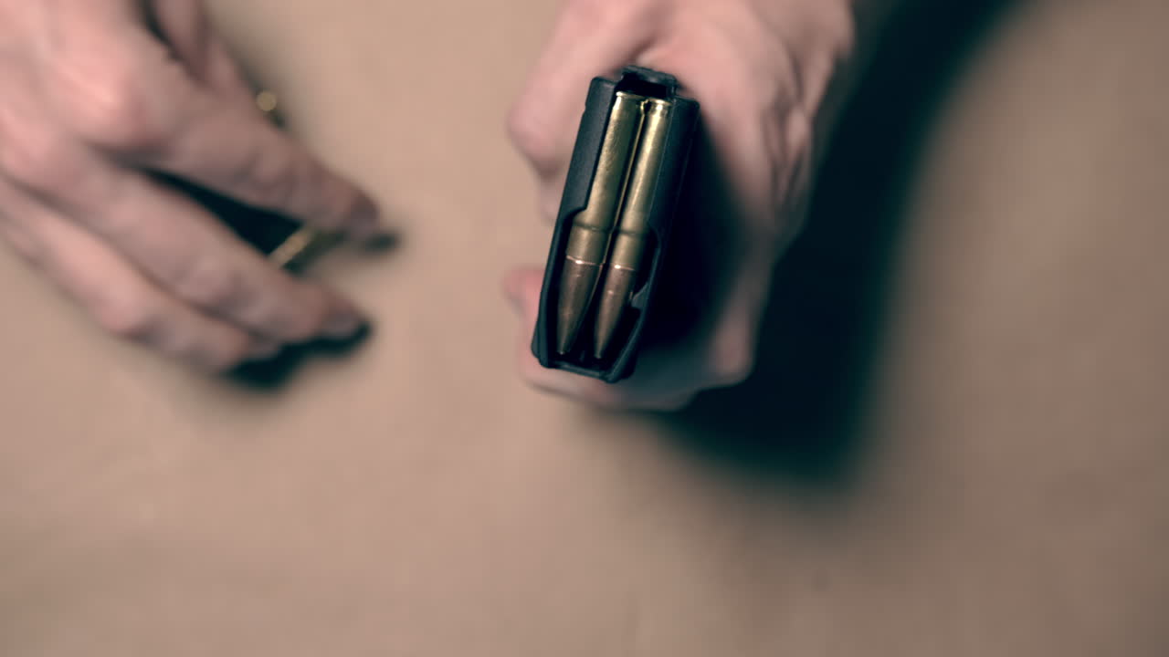 mano masculina cargando una revista de rifle en una mesa interior