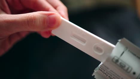 Female-hand-removing-pregnancy-test-indicator-examination-closeup-from-packet