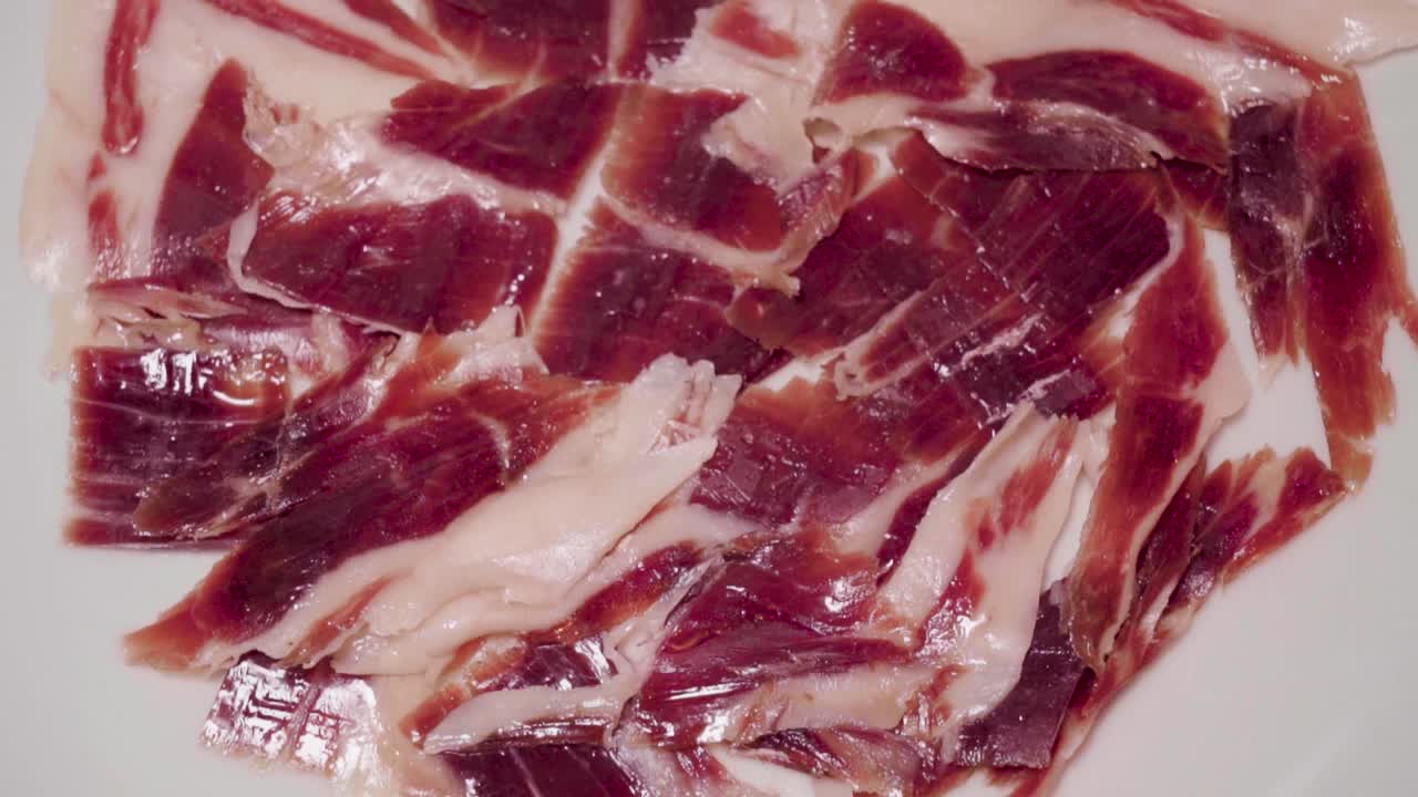 inclinación hacia arriba de jamón ibérico en rodajas sobre fondo blanco aislado, primer plano