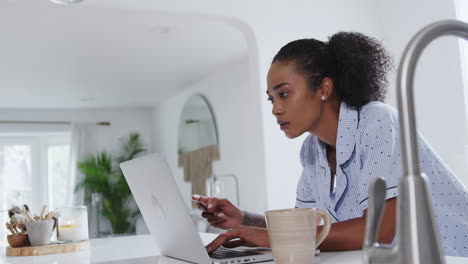 Mujer-En-Pijama-En-La-Cocina-Haciendo-Compras-Con-Tarjeta-De-Crédito-En-Línea-En-Una-Computadora-Portátil