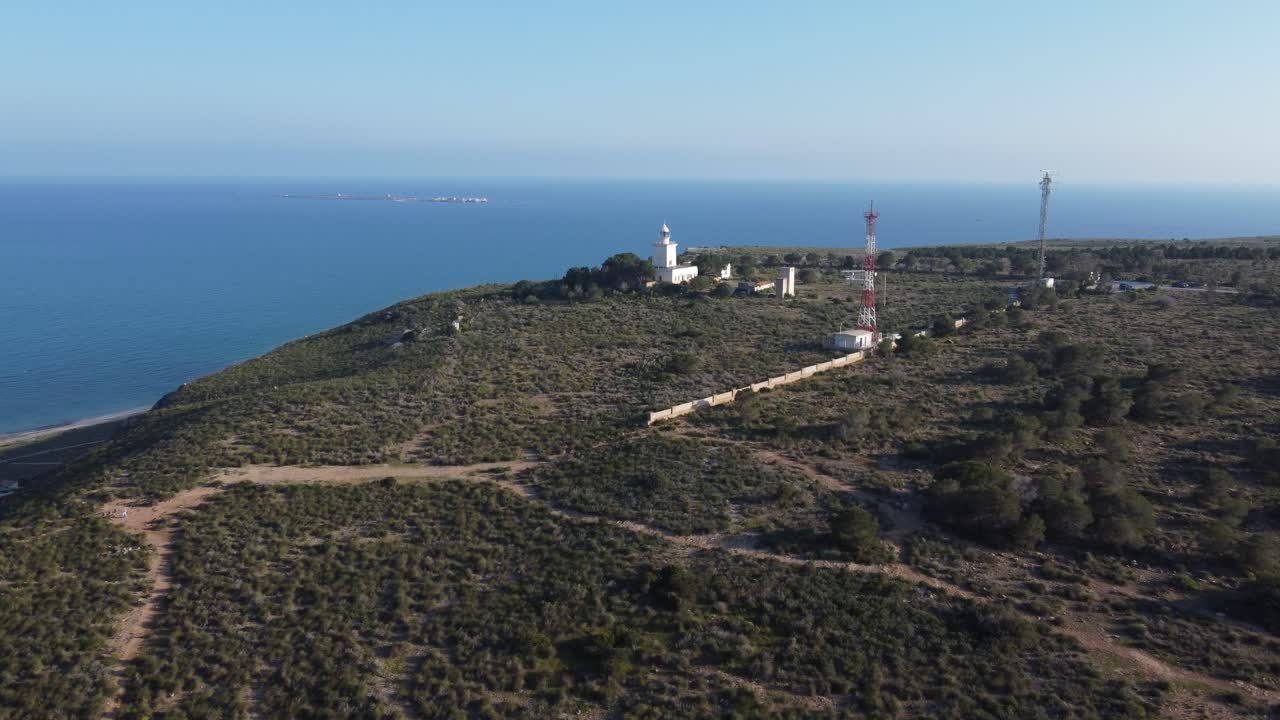 Avvicinamento aereo al faro di Santa Pola in cima alla scogliera. L'isola di Tabarca sullo sfondo. Spagna