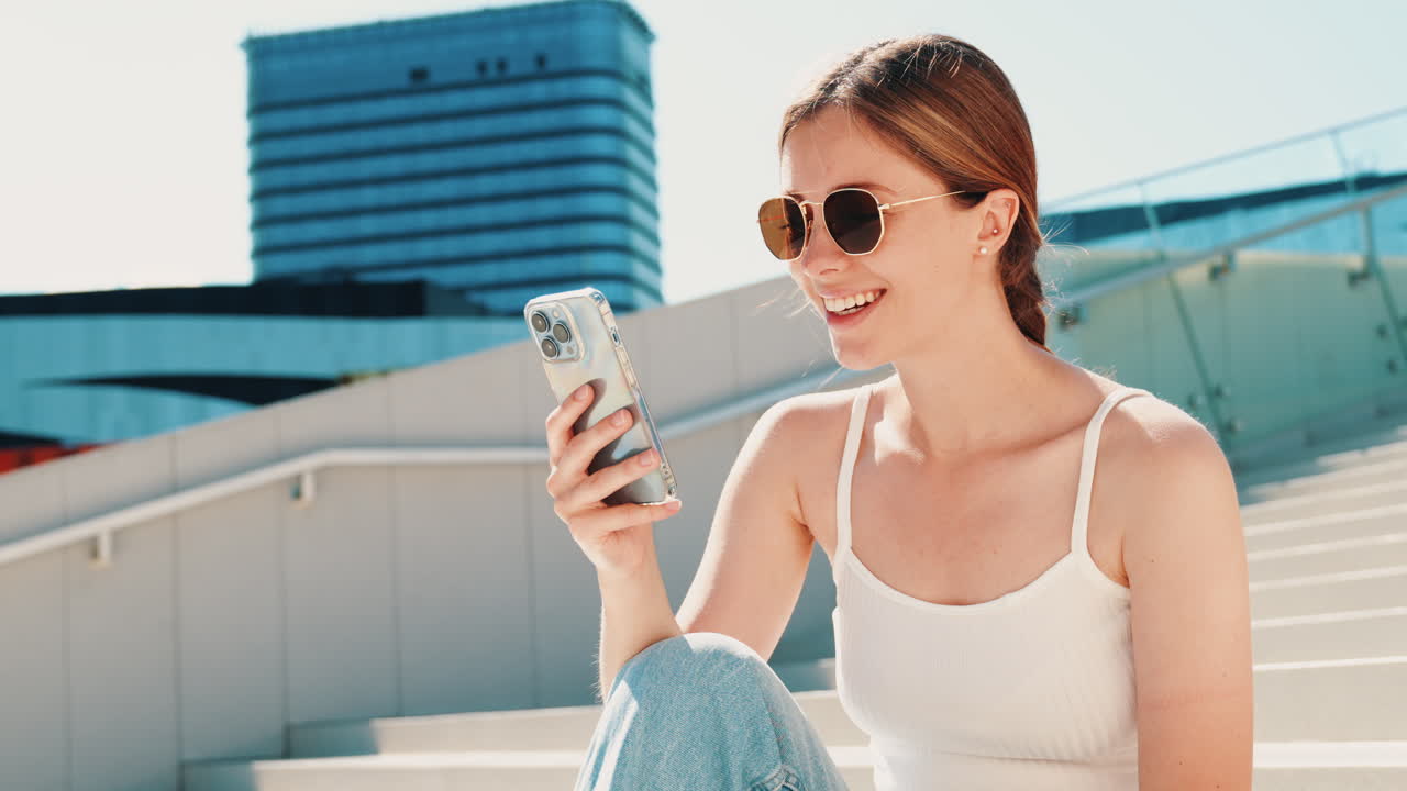 도시 계단에서 스마트폰을 사용하는 행복한 여성