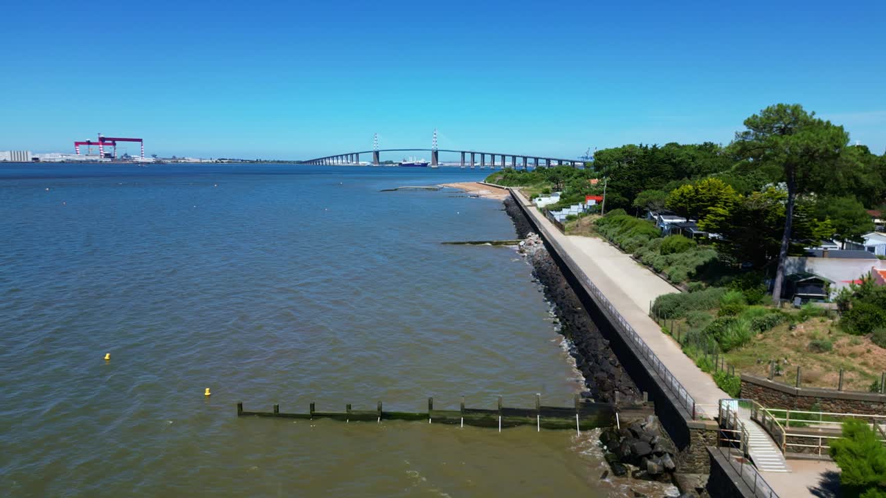 Panoramic View of a Long Bridge Spanning an Estuary with Coastal Path and Distant Industrial Port