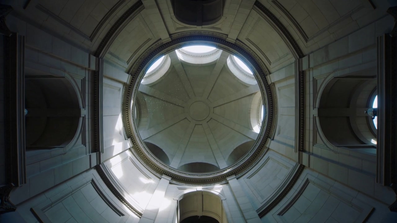 Inclinazione della telecamera che rivela l'interno di una rotonda a cupola in una cappella mentre la luce del sole scopre l'oculo e la cornice.