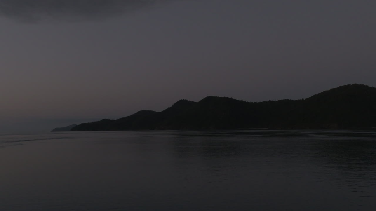 Very early morning drone shot of silhouetted and dark islands in the Whitsunday Islands, QLD, Australia