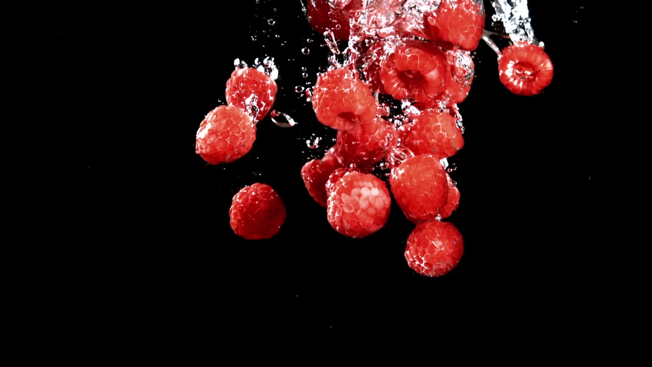 Slow Motion of Fresh Red Raspberries Dropping into Water