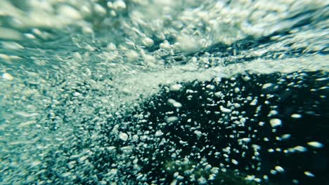 cámara lenta de burbujas de aire flotando desde el fondo del río hasta la superficie del agua