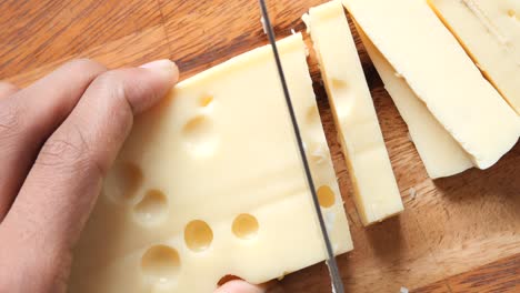 slicing swiss cheese on a wooden cutting board