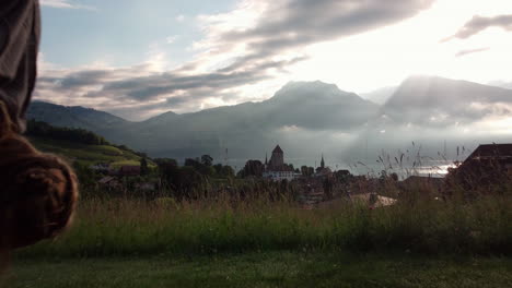 Aerial-view-of-a-woman-doing-yoga-poses-in-front-of-the-skyline-of-Spiez,-Switzerland