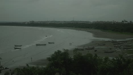 Filmischer-Blick-Auf-Einen-Strand-Am-Abend-Nach-Sonnenuntergang,-Menschen-Gehen-Am-Strand-Spazieren-Und-Ein-Paar-Boote