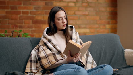 woman reading a book on a sofa