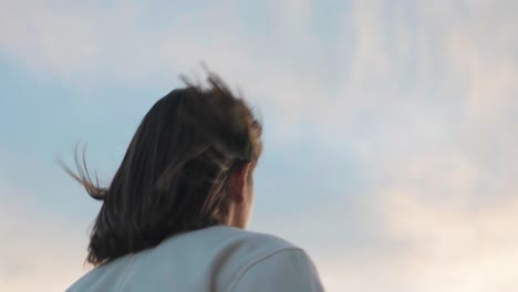 Vista-De-ángulo-Bajo-Del-Aleteo-Del-Cabello-Femenino,-El-Exterior-Del-Edificio-Y-El-Fondo-Del-Cielo