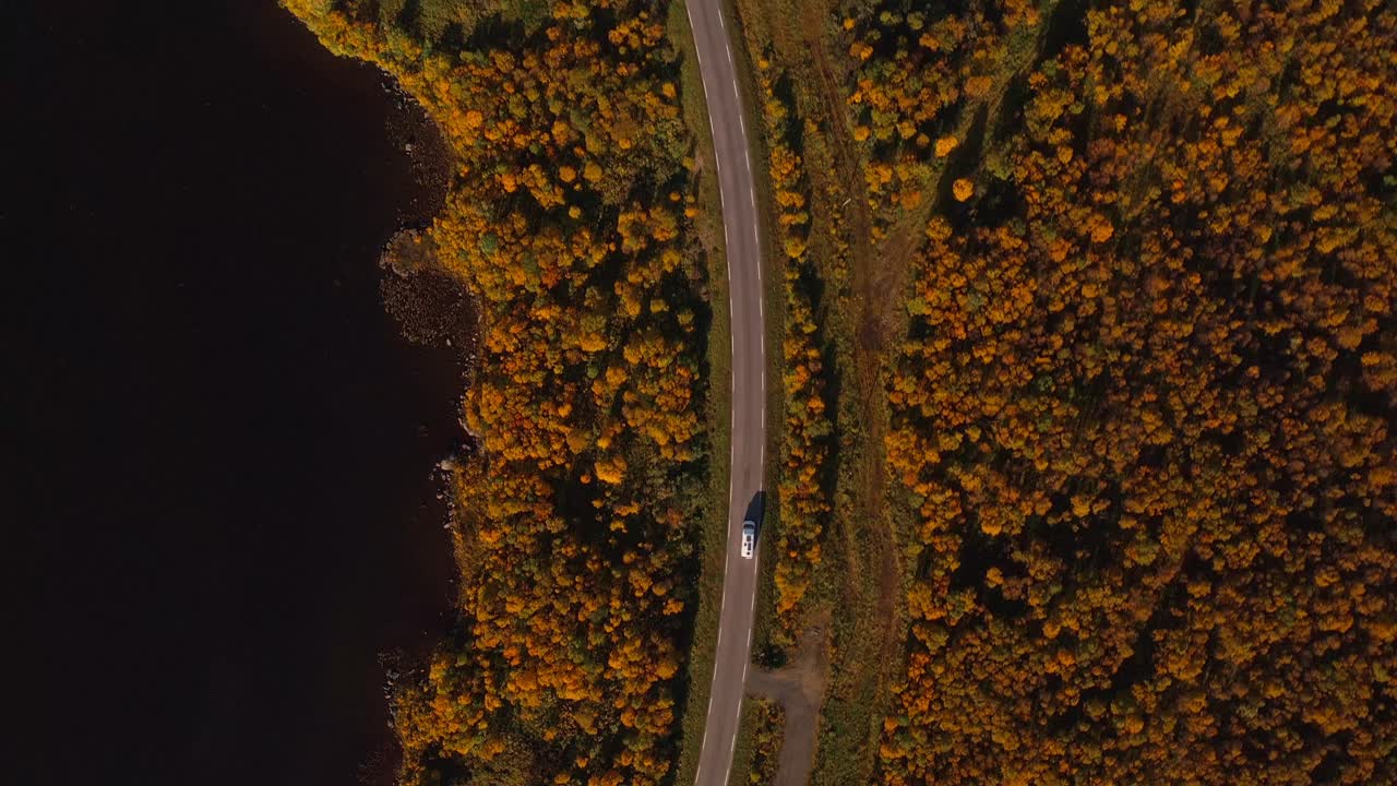 A scenic aerial view of a winding road amidst vibrant autumn-colored trees in Vestarelen