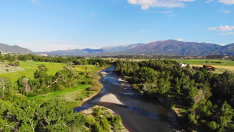 flache flusslandschaft, gesäumt von üppigen grünen bäumen im colorado rocky mountain valley