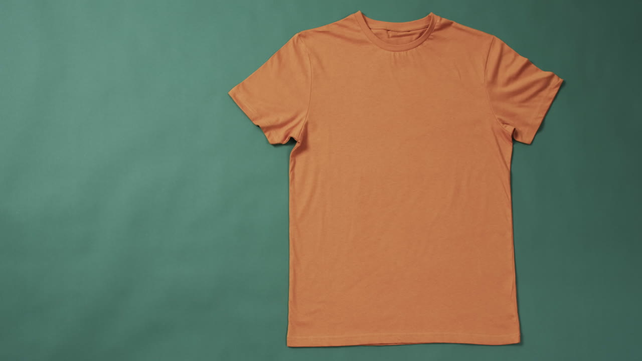 video de camiseta naranja con etiqueta y espacio de copia en fondo verde