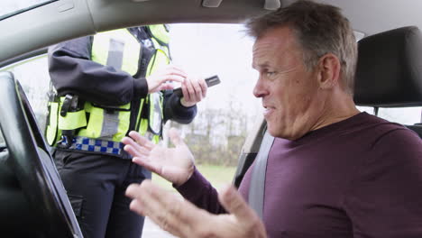 male driver being stopped by female traffic police officer with digital tablet for driving offence