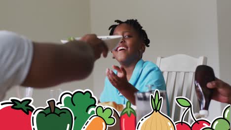 Multiple-vegetables-icons-against-african-american-man-passing-a-bowl-on-dining-table-at-home