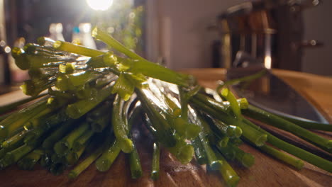 wide macro shot of a bunch of chives falling on a wooden cutting board