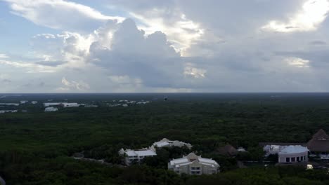 Beautiful-aerial-drone-shot-following-a-large-bird-in-the-tropical-coastline-of-playa-del-carmen-with-large-vacation-resorts-in-Riviera-Maya,-Mexico-on-a-warm-sunny-summer-day