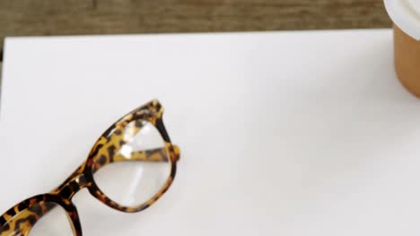 papel en blanco con café y gafas en una mesa de madera 4k