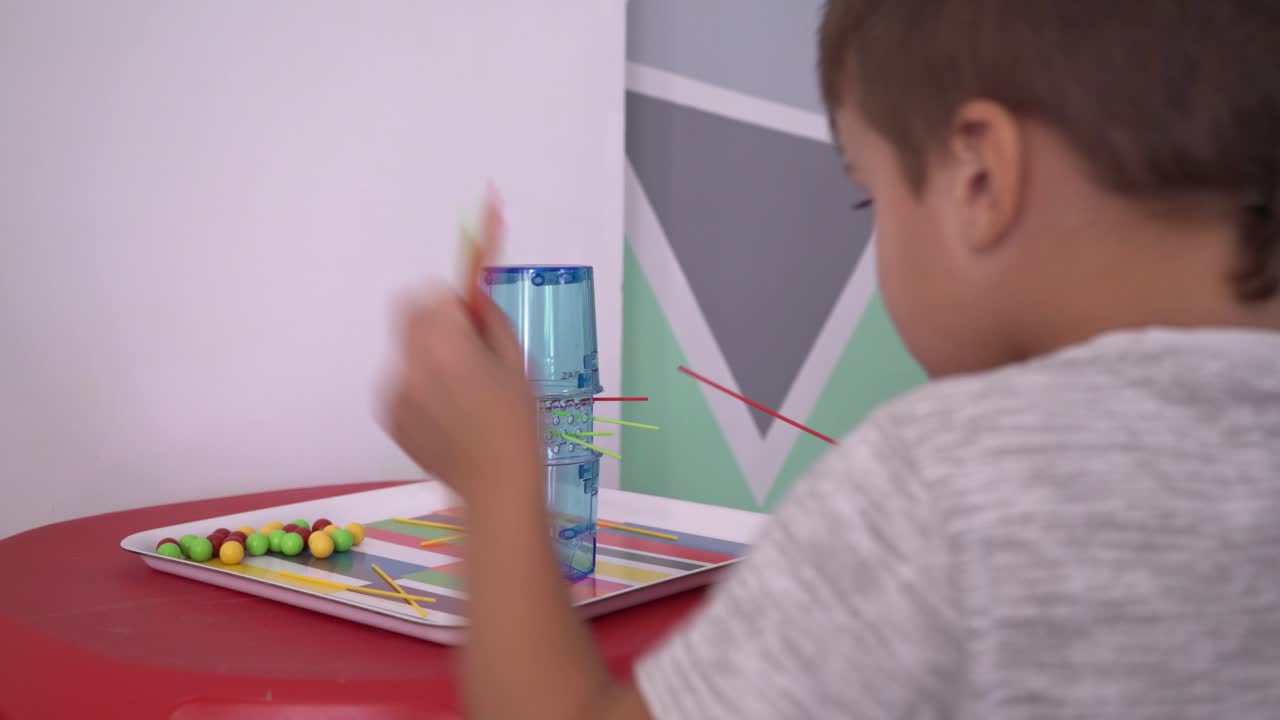 niño caucásico de cuatro años jugando al juego clásico kerplung en casa, vista trasera 4k