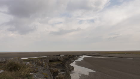 time-lapse on the coastline of england with tide out, some people out walking