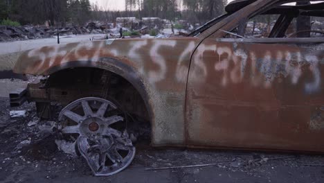 Slider-shot-across-side-of-burned-car-in-Paradise,-California-wildfire-aftermath