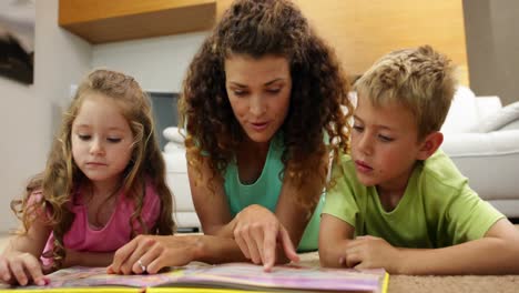 Siblings-lying-on-floor-reading-book-with-mother