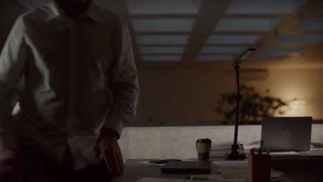 tired businessman closing laptop, leaving office workplace at night