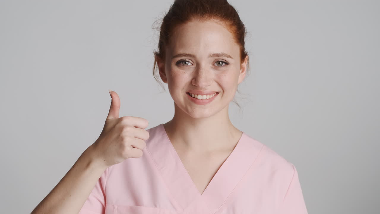 Redheaded doctor in front of camera on gray background.
