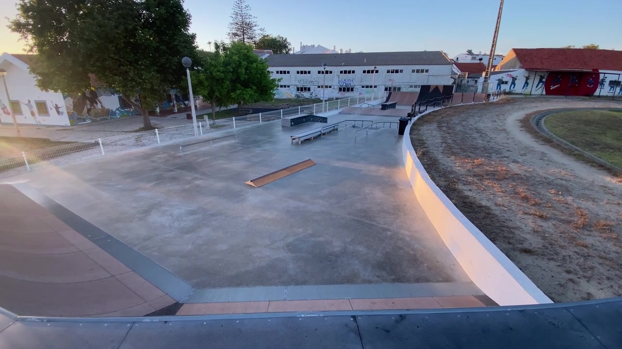 Leeg skatepark met ramps en rails onder de zachte ochtendzon in een rustige stadswijk in Alentejo, Portugal.