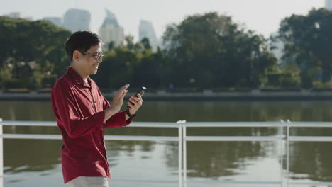 man using phone by the river