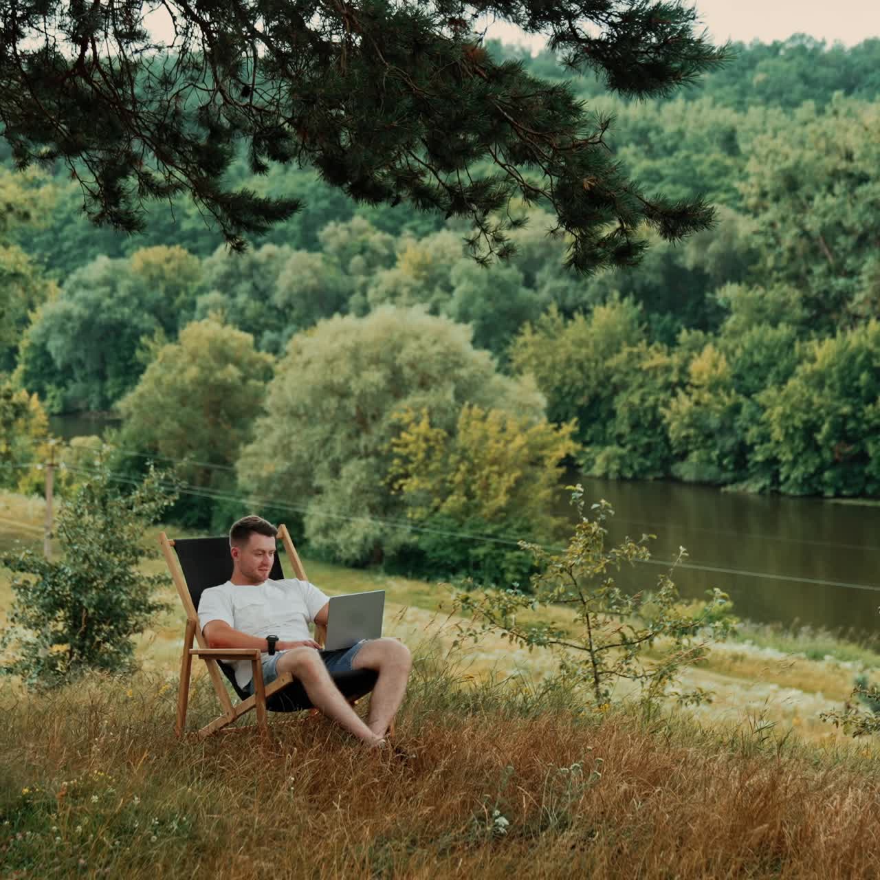 Man sits in a nature working on his laptop. Freelance lifestyle outside the office
