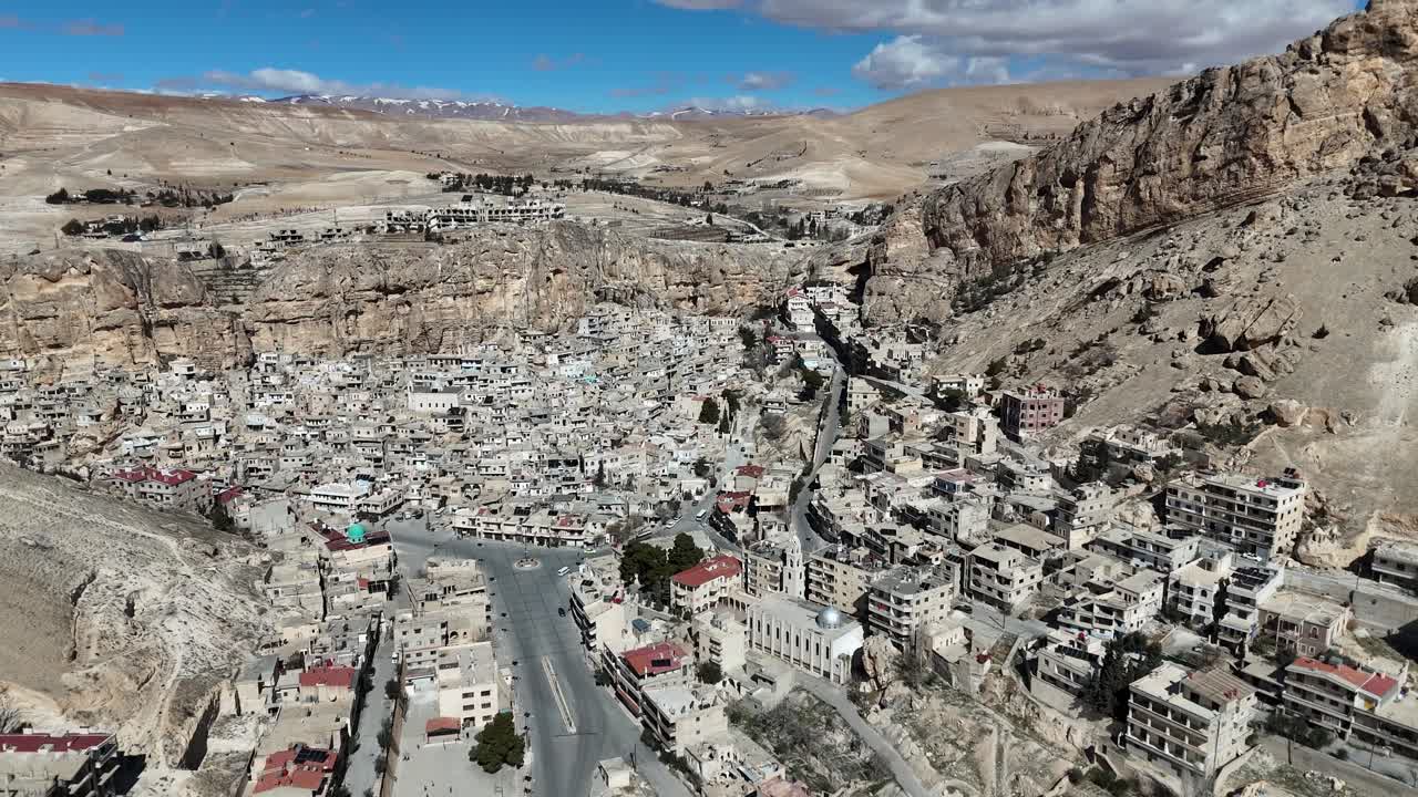 Cinematic perspective of the ancient village of Ma'loula, Syria, showing architecture into the steep Qalamoun Mountains