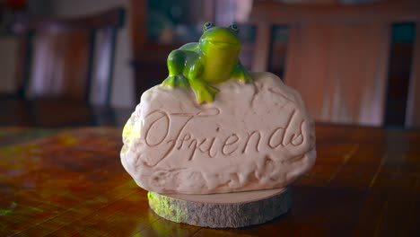 Green-Ceramic-Frog-Sitting-On-Carved-Stone-With-Word-Friends-Written-On-It