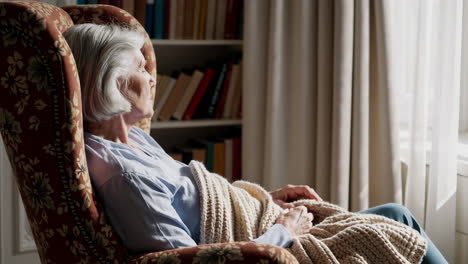 elderly woman relaxing in an armchair at home